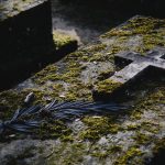 A moss-covered tombstone with a cross