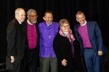 Image Description: A photo of the five bishops who were nominated to stand for election for the 28th presiding bishop of The Episcopal Church. They are all wearing shades of their purple clerical shirts and smiling, apparently, towards a different camera than the one that took this photo. From left to right, the Rt. Rev. Sean Rowe, the Rt. Rev. Rob Wright, the Rt. Rev. Daniel Gutierrez, and the Rt. Rev. Scott Barker.