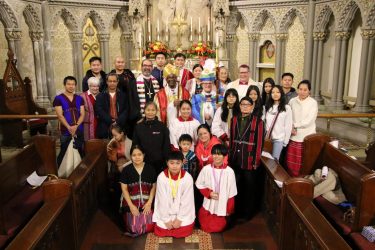 Image Description: A group of Karen families from Grace Episcopal Church in Utica, NY pose in the sanctuary of the church in front of the altar with Presiding Bishop Michael Curry, Bishop DeDe Duncan-Probe, Bishop Lee Miller II of the Upstate NY Synod of the ELCA, and Bishop Douglas Lucia of the Roman Catholic Diocese of Syracuse after a diocesan event in December of 2023.